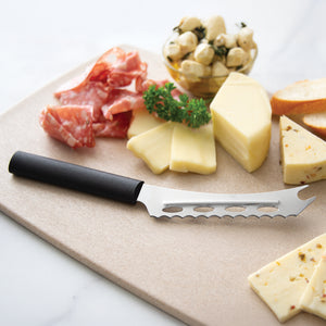Cheese platter with sliced cheese, cured meats, and a black handle cheese knife on a wooden board.