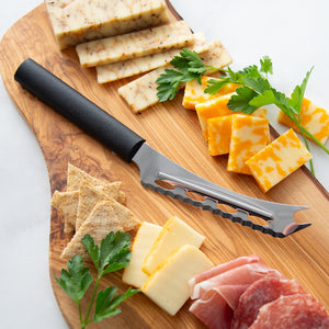 Wooden cutting board with cheese, crackers, and a knife on a white background