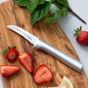Silver handle knife on a cutting board with strawberries, greenery, and lemon