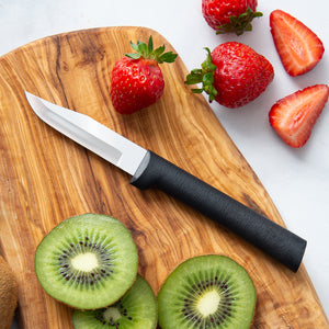 Black handle knife on a cutting board with strawberries and kiwi