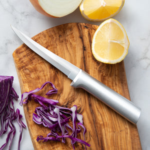 Wooden cutting board with a knife, sliced purple cabbage, and lemon halves on a marble surface.