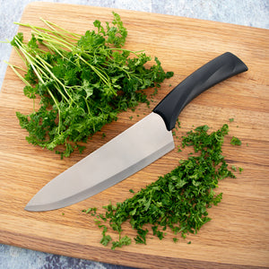Rada Cutlery Anthem Wave French Chef Knife with minced herbs on a wooden cutting board.
