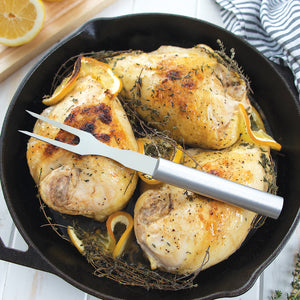 Rada Cutlery Carving Fork with silver handle on chicken pieces in cast iron pan.