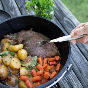 Rada Cutlery's silver handle Carving Fork lifting a roast out of a pot on a picnic table.