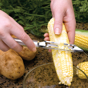 Deluxe Vegetable Peeler with silver handle using on sweet corn.
