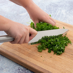 Using the Rada French Chef Knife to chop fresh parsley on a wooden cutting board.