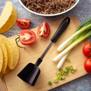Rada's four blade Meat Chopper next to unmade tacos with onions, tomatoes, shells and meat.