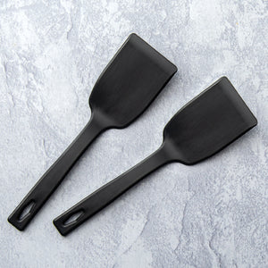 Two small black nylon spatulas on countertop.