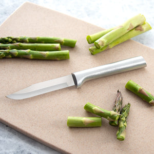 An aluminum handled Rada Cutlery regular paring knife on a cutting board with cut asparagus.