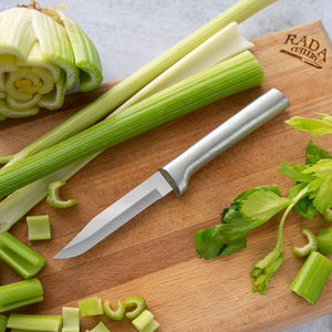 Silver Serrated Regular Paring on a cutting board with whole and chopped up celery.