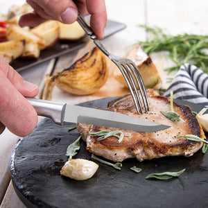 Serrated Steak Knife with silver handle ready to cut pork chop.