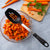 Chopped carrots with leafy greens, a cutting board and whole carrots with Rada's Basting Spoon.