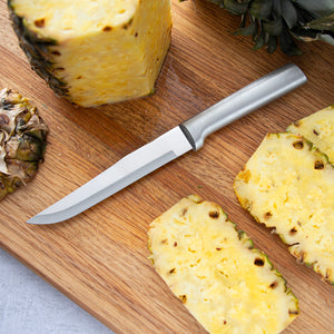 Silver handle Stubby Butcher laying on a cutting board next to a pineapple with the sides cut off.