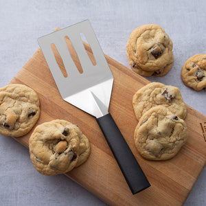 Black handle Turnover with chocolate chip cookies on a cutting board.