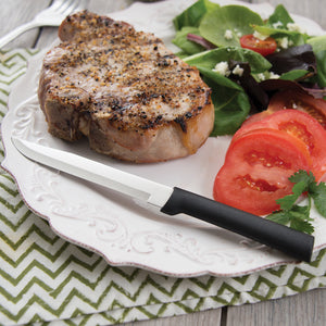 Rada Cutlery Utility/Steak Knife with black handle on plate with grilled meat, spinach & tomatoes.