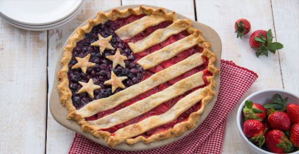 Strawberry and blueberry USA-themed pie beside bowl of strawberries