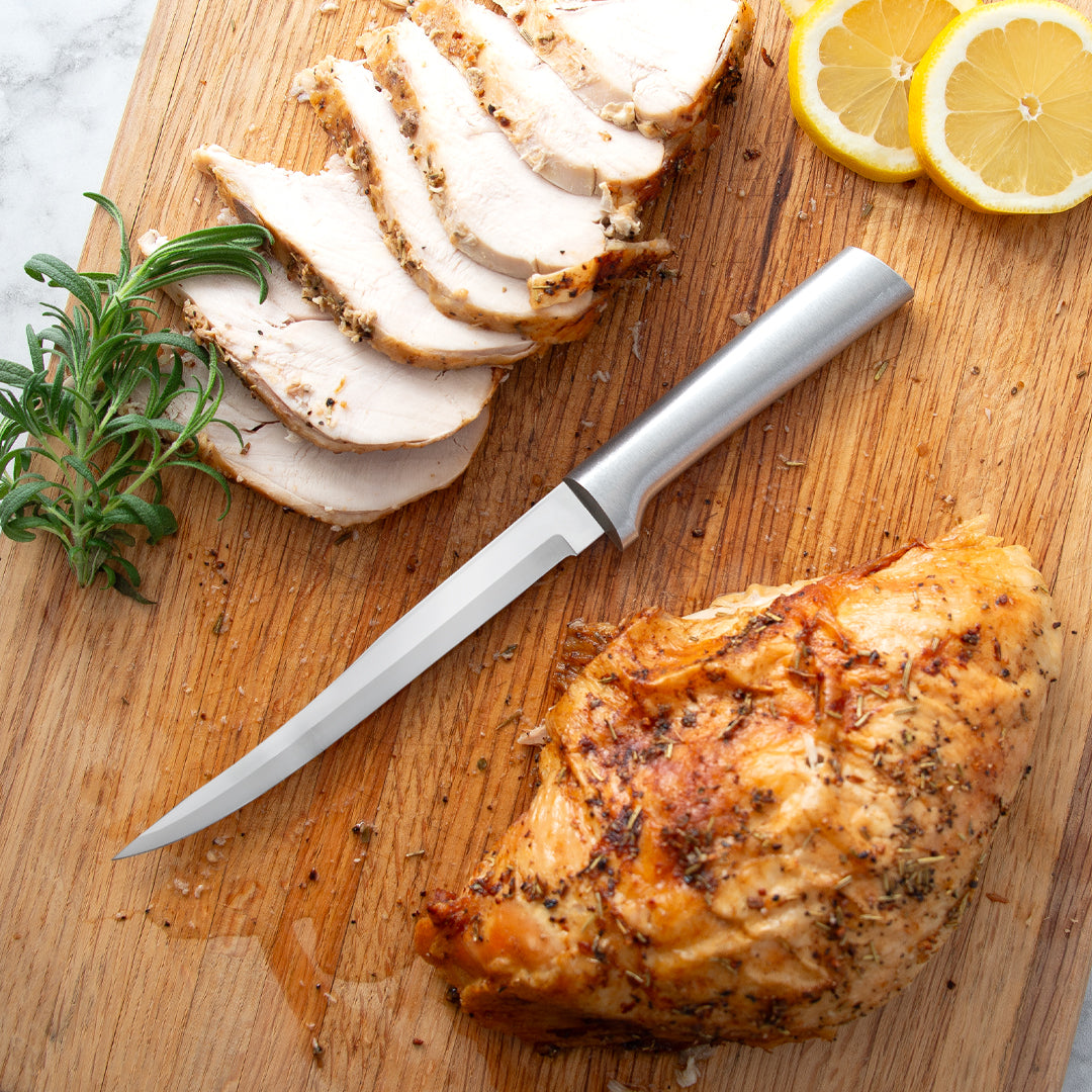 Silver handle knife of a cutting board with chicken and lemon