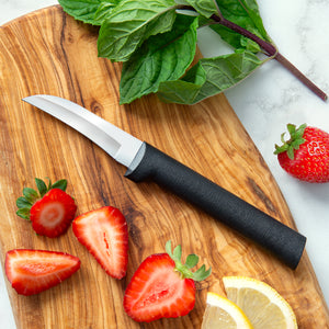 Black handle knife on a cutting board with strawberries, greenery, and lemon