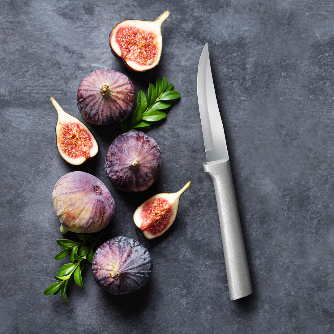 Figs and a knife on a dark surface