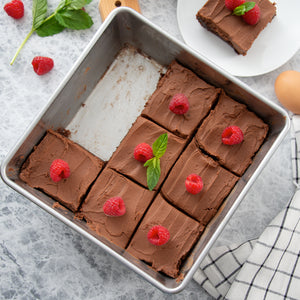 A Rada Square Pan used to make chocolate cake with raspberries and mint leaves on a white marble surface.