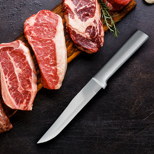 Raw steaks on a wooden board with a knife on a dark surface