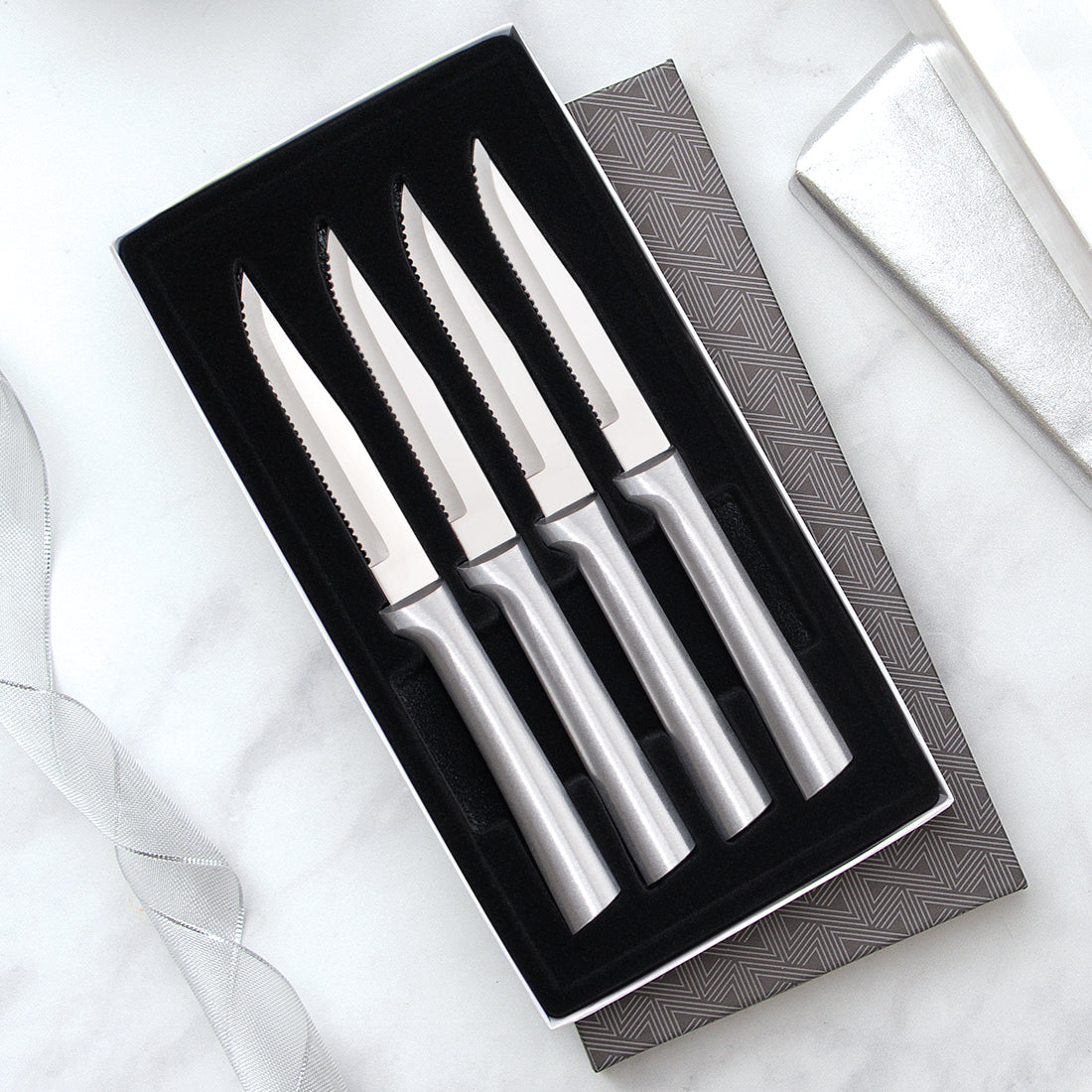 Four Serrated Steak Knives Gift Set with silver handles in a black-lined gift box