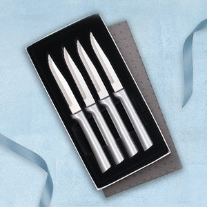 A gift box with the lid off showing four Rada Cutlery serrated steak knives with silver, brushed aluminum handles.