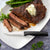 Rada Cutlery Anthem Wave Serrated Steak knife on white plate with sliced steak