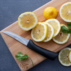 Rada Anthem handle Super Parer Knife laying on it's side on a cutting board next to already sliced lemons.
