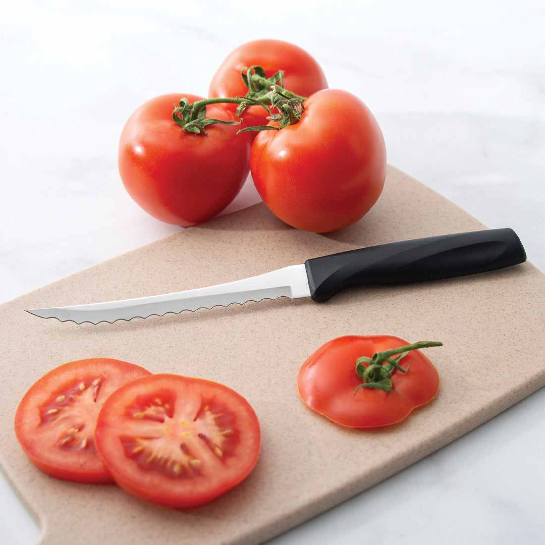 Rada Cutlery Anthem Wave Tomato Slicer on a cutting board with sliced tomatoes