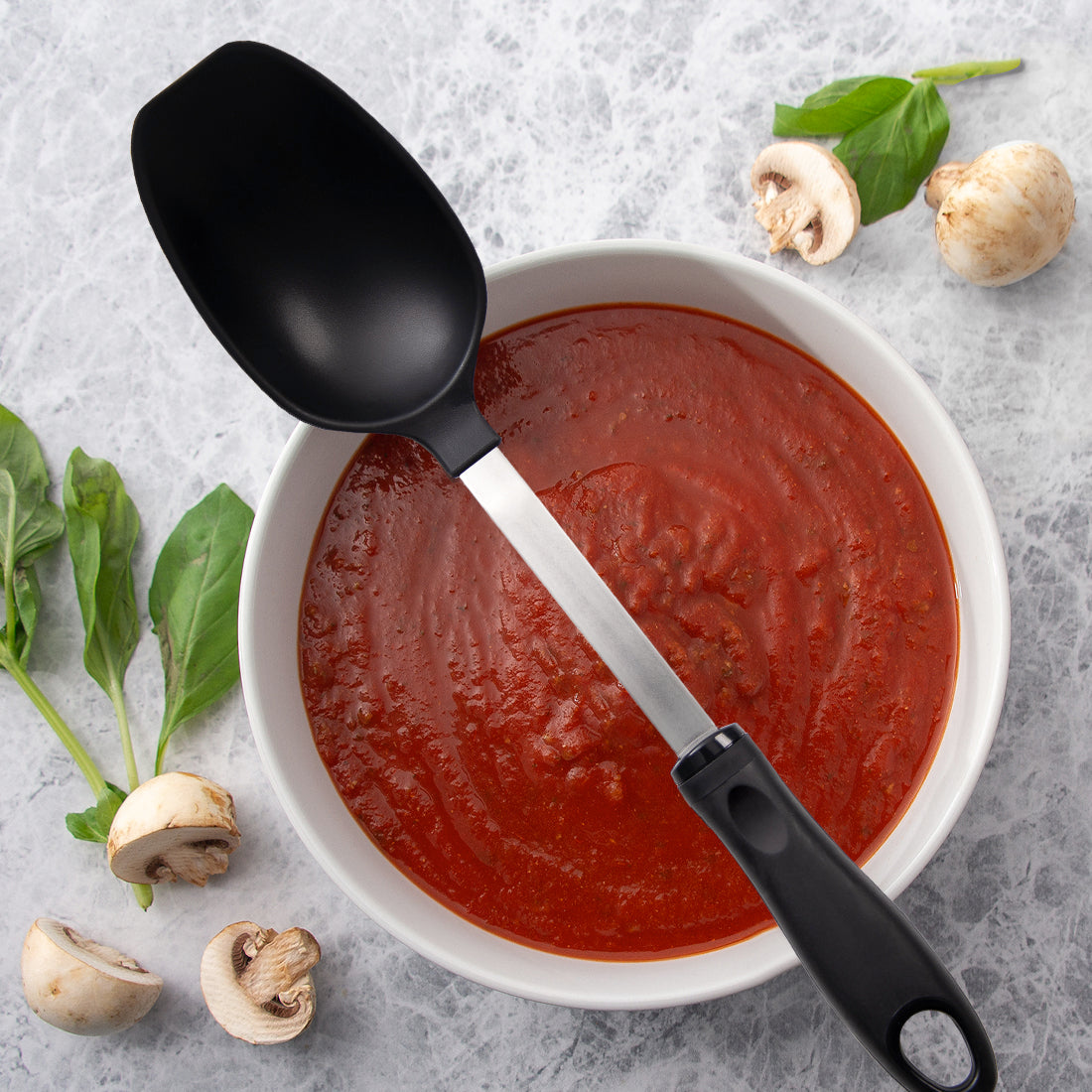 Basting Spoon over red sauce, mushrooms, and leafy greens.