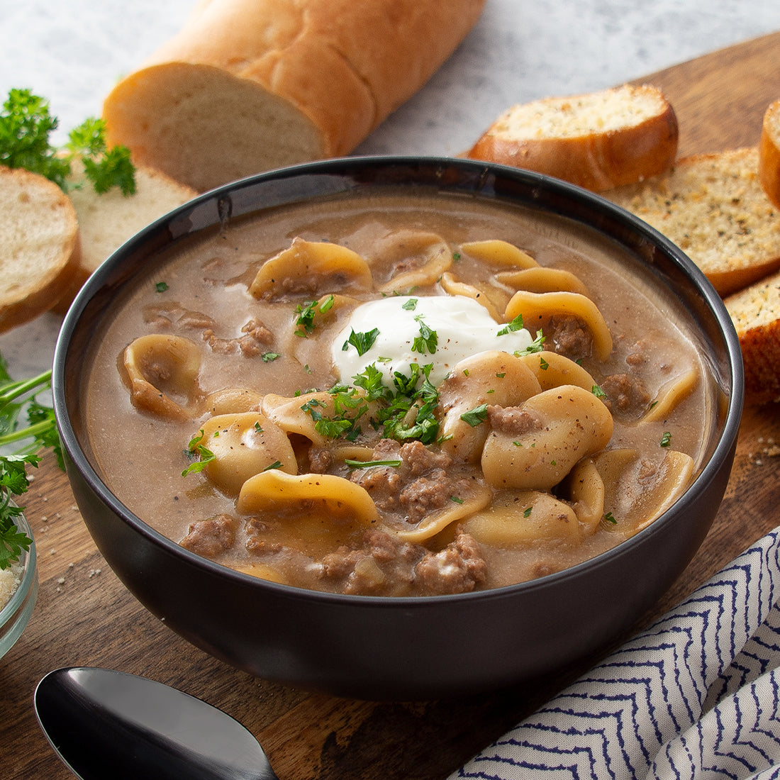 Prepared Beef Stroganoff Soup in bowl garnished with parsley and sour cream. 