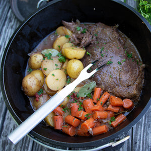 Rada's Carving Fork in a pot on a picnic table with potatoes, carrots, and a roast.