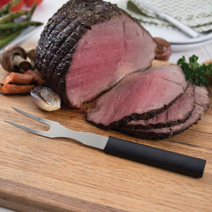 Carving Fork with black handle on cutting board with sliced ham. 