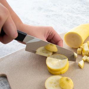 Rada's Black Handle Cook's Knife chopping and cutting a squash on a cutting board.