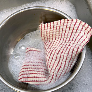 Dishcloths in a bowl soaking in suds to be cleaned out in the sink.