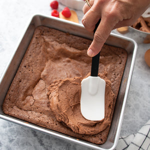 Spreading chocolate frosting over pan of brownies with the flexible spatula. 