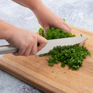 Using the Rada French Chef Knife to chop fresh parsley on a wooden cutting board. 