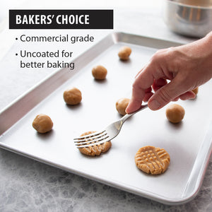 Fork flattening cookie dough on Half Sheet Pan. Commercial grade, uncoated for better baking. 
