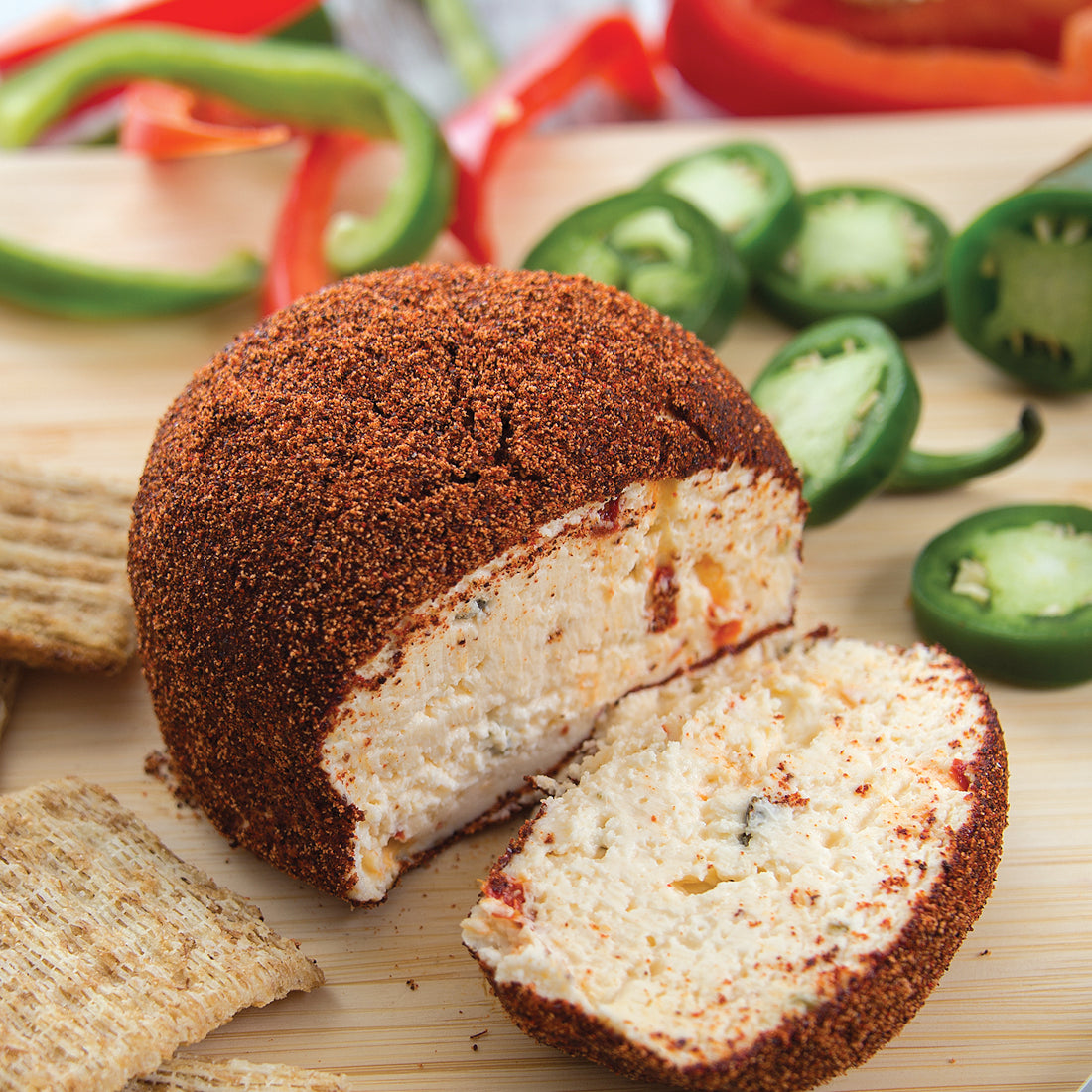 Sweet Hot Pepper Jelly Cheeseball sliced with crackers and jalapenos. 
