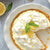 Lemon Drop No-Bake Cheesecake in pie dish garnished with lemon slices, lemon zest, and mint. 