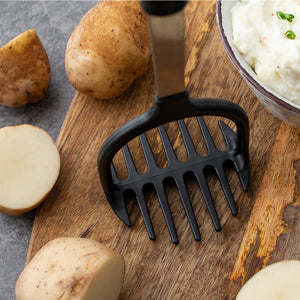 Non-scratch Potato Masher standing upright on cutting board with potatoes