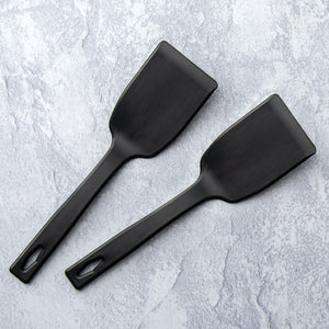 Two small black nylon spatulas on countertop. 