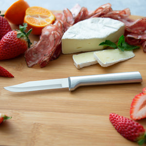 An aluminum handled regular paring knife on a cutting board with slices of cheese, prosciutto, strawberries and oranges. 