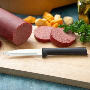The Rada Cutlery regular paring with a black resin handle on a cutting board next to sliced summer sausage. 