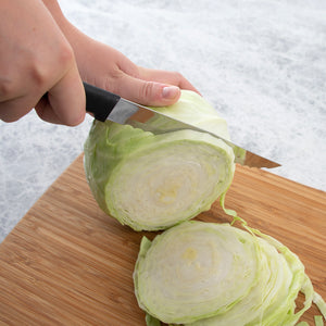 Serrated Slicer slicing cabbage thin on a cutting board.
