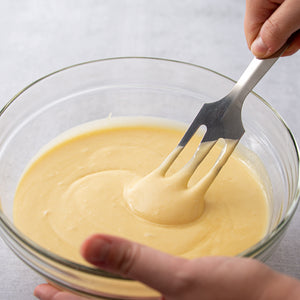 Rada Kitchen Store Serverspoon in yellow cake batter, stirring and mixing it up in a glass bowl.