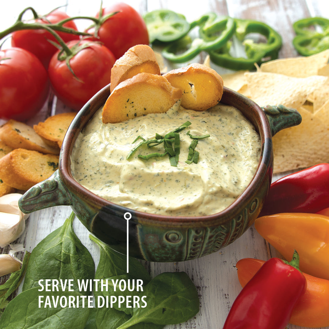Serve with your favorite dippers. A bowl of spinach artichoke dip with bread, tortilla chips, sweet peppers and tomatoes. 