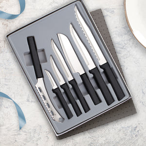 The seven piece Rada Cutlery Starter Gift Set Part 2 with black handles on a marble countertop with a blue ribbon. 