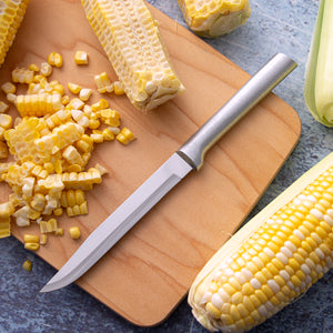 A silver Utility/Steak Knife on a wood cutting board with whole and sliced corn.